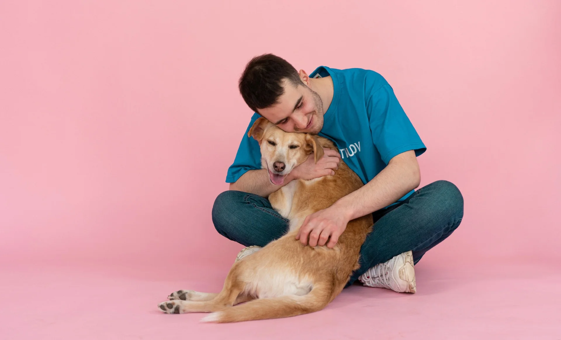homem sentado abraçando um cachorro