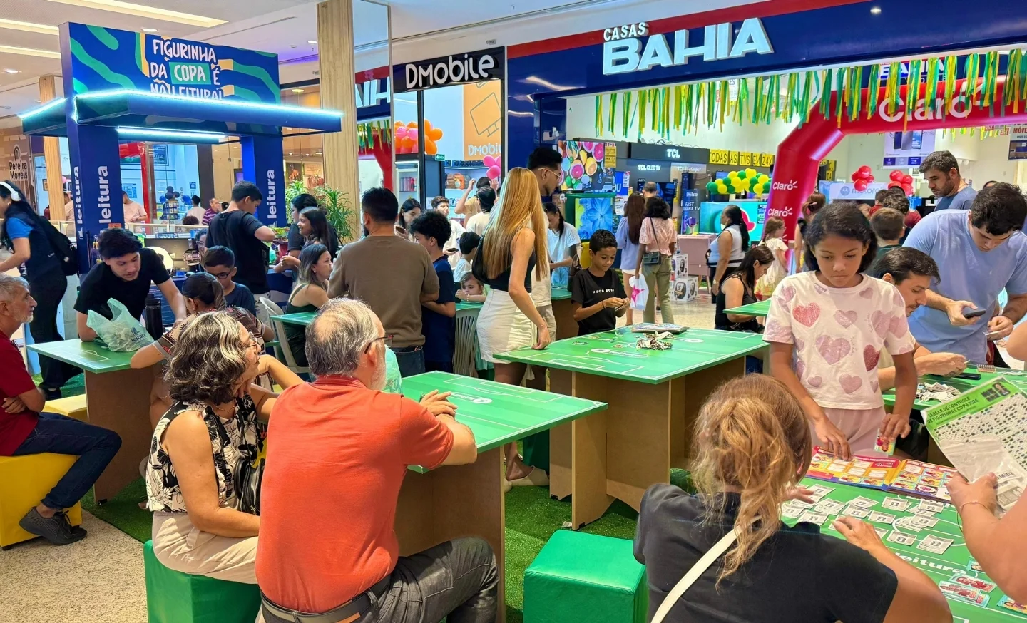 Pessoas reunidas no ponto de troca de figurinhas da copa, localizado em frente à loja Casas Bahia