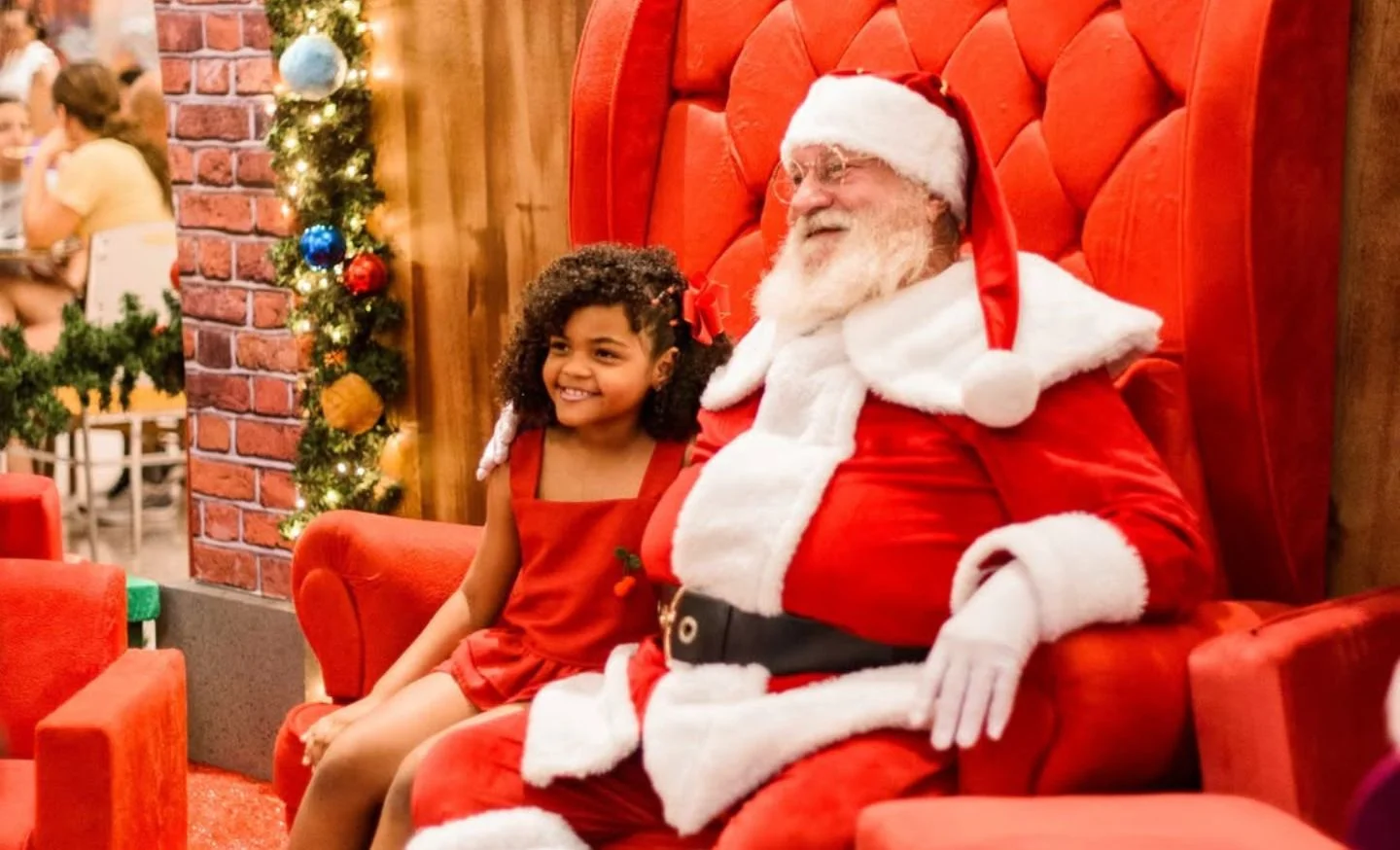 Papai Noel no trono sentado ao lado de uma criança